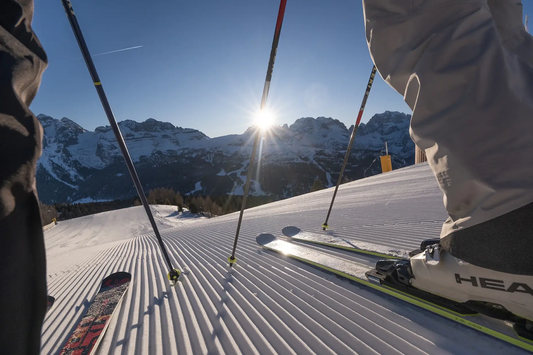 Sciare all'alba su una pista innevata con le montagne sullo sfondo.