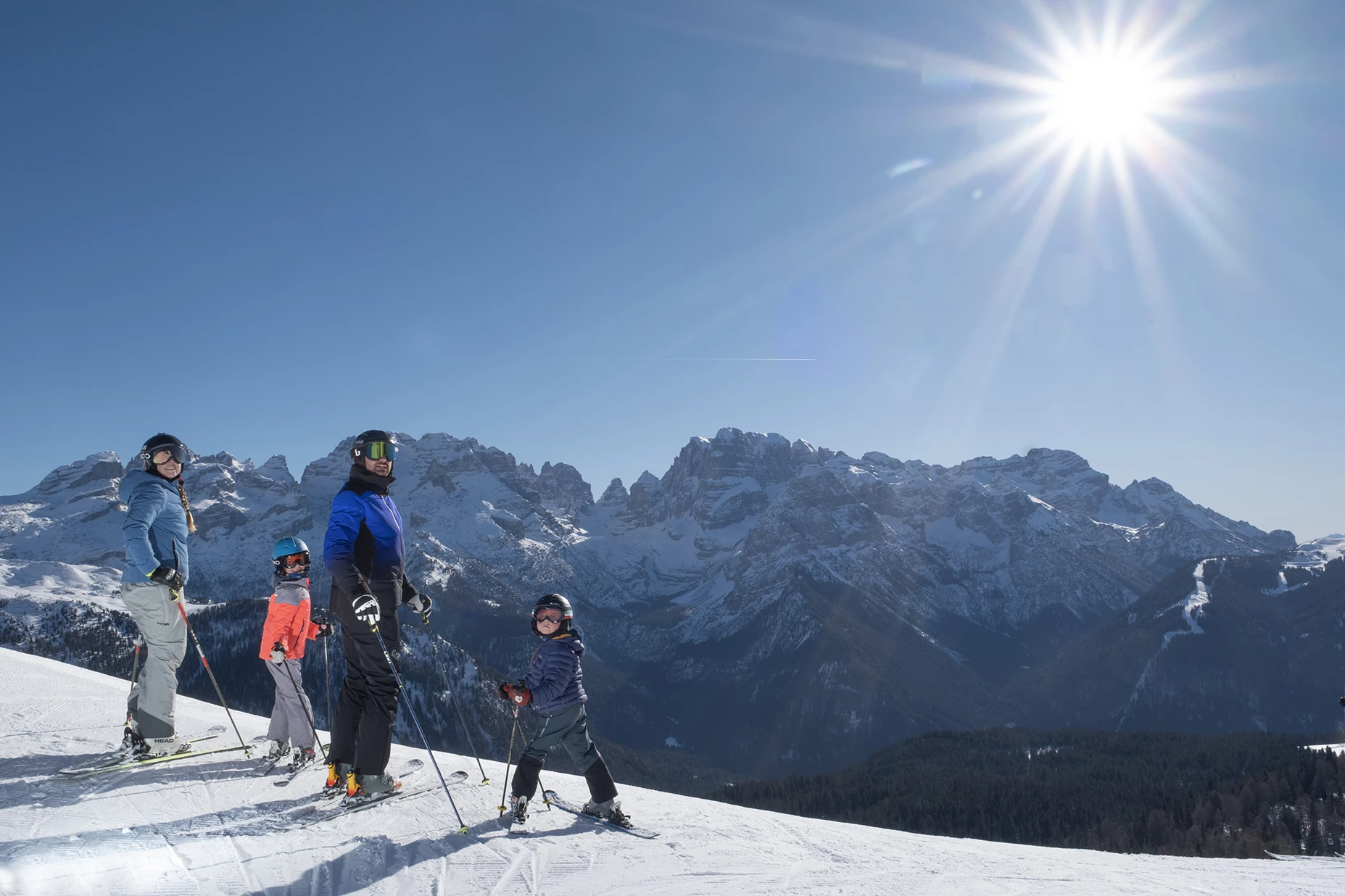 A family skiing on a snowy mountain under a bright sun.