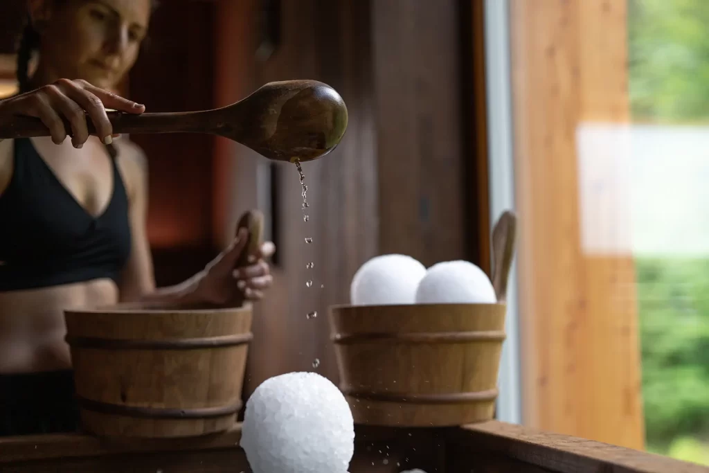 Donna che versa acqua su una palla di ghiaccio in una sauna.